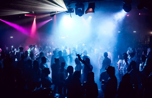 Tanzende Menschen in einem Club mit blau-violetten Lichteffekten.