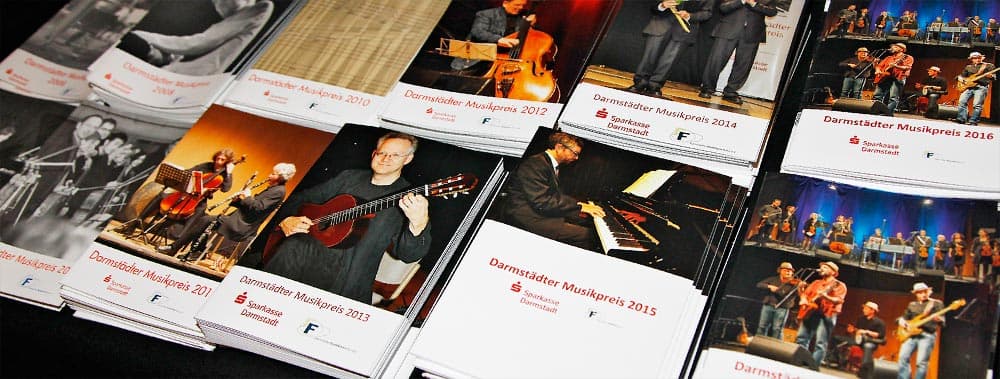 Das Foto zeigt sechs Stapel von Programmheften des Musikpreises aus einem vergangenen Jahr.