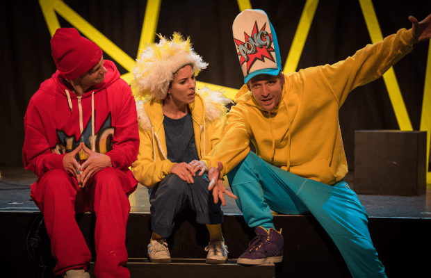 Die Band ‚Eule findet den Beat‘ auf der Bühne, zwei Männer und eine Frau; sie tragen farbenfrohe Kostüme und Kopfbedeckungen.